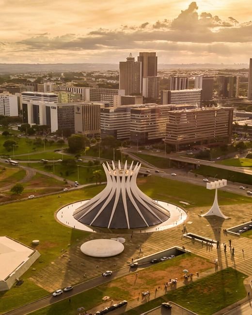 Vista aérea de Brasília ao entardecer, com a Catedral Metropolitana e o Setor Comercial Norte